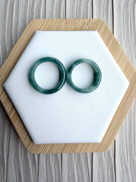Dreamy Jade pair of polished natural green jadeite bangles with unique marbling on a white hexagonal display stand