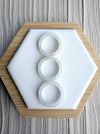 Three Dreamy Jade natural stone band rings with smooth polished finish arranged vertically on a white hexagonal stand