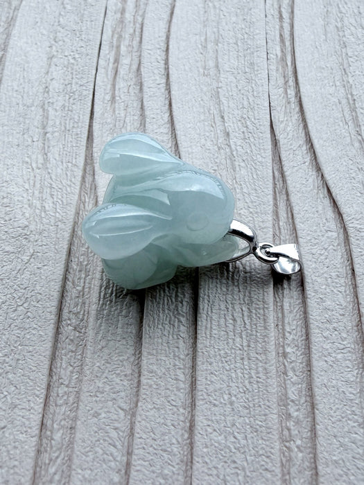Dreamy Jade elegant pale green carved jade rabbit pendant with a polished silver-tone bail on a textured surface