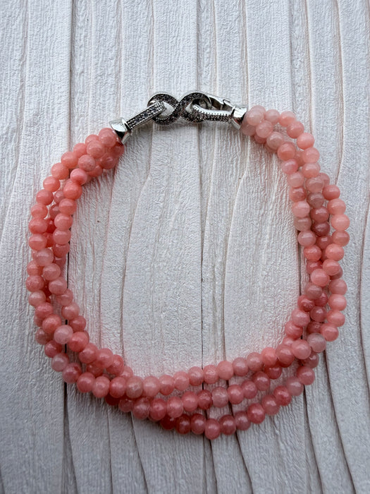 Dreamy Jade triple-strand pink gemstone beaded bracelet with a silver-tone infinity clasp featuring pavé crystals.