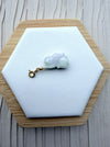 Dreamy Jade hand-carved rabbit charm in pale green jade with a gold-tone clasp on a white hexagonal display stand.