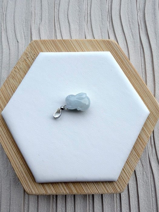 Dreamy Jade rabbit pendant carved from translucent light grey jade with a polished silver-tone bail on a display base.