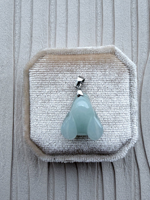 Dreamy Jade pale green carved rabbit pendant with a silver-tone bail resting on a beige velvet jewellery box