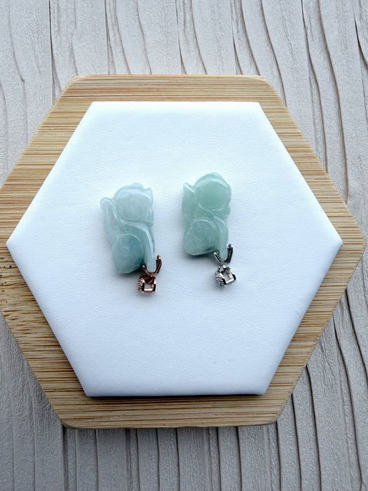 Dreamy Jade rabbit pendants in translucent green jade with rose gold and silver pavé-set stone bails on a display base.