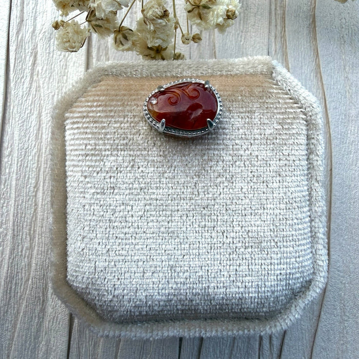 Dreamy Jade red jadeite pendant with intricate hand-carved swirling motifs set in a silver-tone frame with crystal.