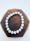 Dreamy Jade round bead bracelet featuring polished natural jadeite in soft mint green and lavender hues on wood base