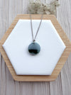 Dreamy Jade round green jade pendant necklace on a silver chain with a floral-inspired bail on a white display stand.
