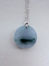 Dreamy Jade round pendant necklace featuring a smooth green jade disc on a silver-tone chain with a floral-style bail.
