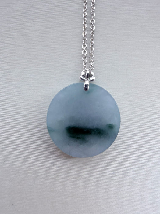 Dreamy Jade round pendant necklace featuring a smooth green jade disc on a silver-tone chain with a floral-style bail.
