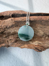 Dreamy Jade round pendant necklace featuring a green jade disc with a floral silver bail on a delicate chain.