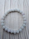 Dreamy Jade round bead bracelet featuring smooth, polished white natural jade stones on a textured light background.