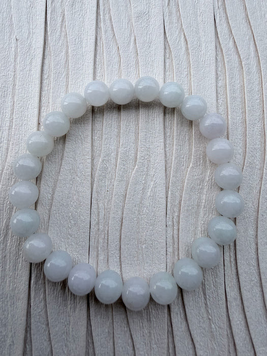 Dreamy Jade round bead bracelet featuring smooth, polished white natural jade stones on a textured light background.